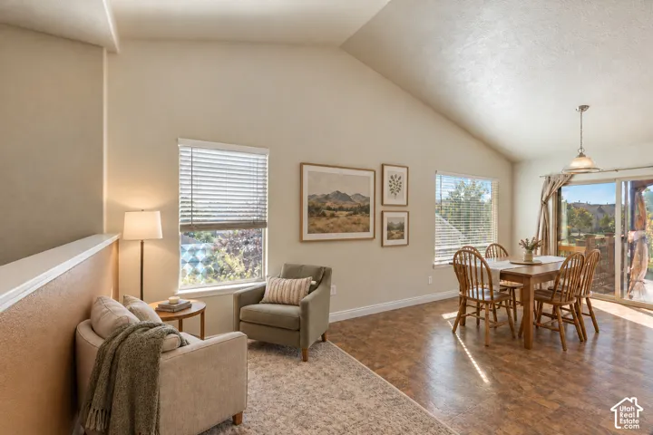 Vaulted ceilings, multiple windows, neutral interior walls, and sliding glass door with external access