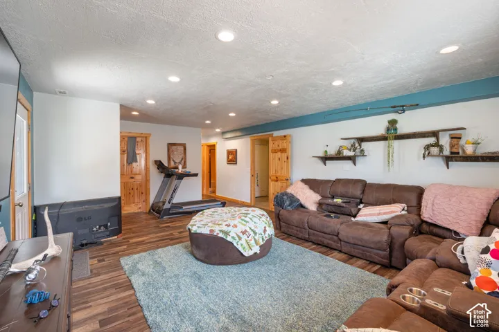 Living area featuring wood-finish flooring, recessed lighting, and wall-mounted wooden shelving