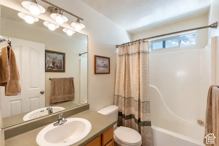Bathroom featuring a solid-surface vanity countertop, an integrated oval sink, a multi-light fixture, a large wall-mounted mirror, and a built-in shower and tub surround