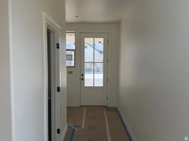 Entryway with a white paneled door and glass inserts, transom window, and an interior door with dark hardware