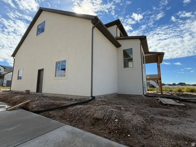 Stucco exterior with brown trim, covered porch with wood supports, and multiple windows
