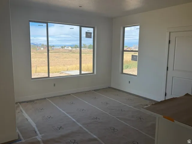 Large window offering expansive outdoor scenery, painted interior door, white wall finishes, and protective floor covering
