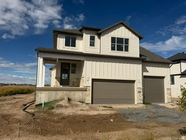 Two-story residence featuring light-toned vertical siding, stone veneer accents, and a covered porch with substantial columns