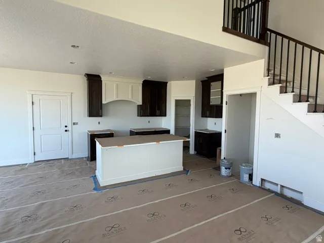 Kitchen featuring a central island, dark wood cabinetry, and a light-colored range hood