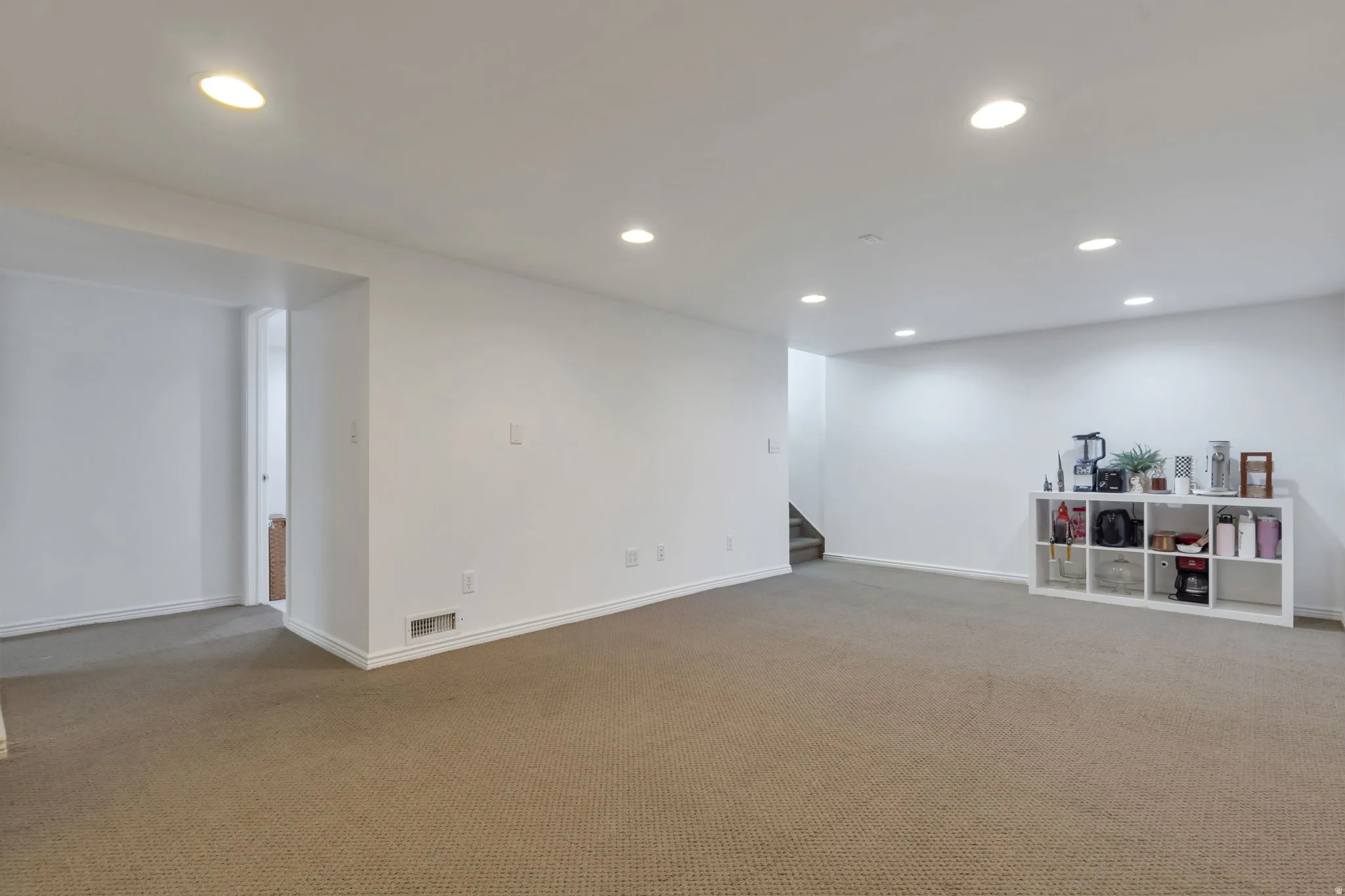 Expansive carpeted room with recessed lighting and neutral wall finishes