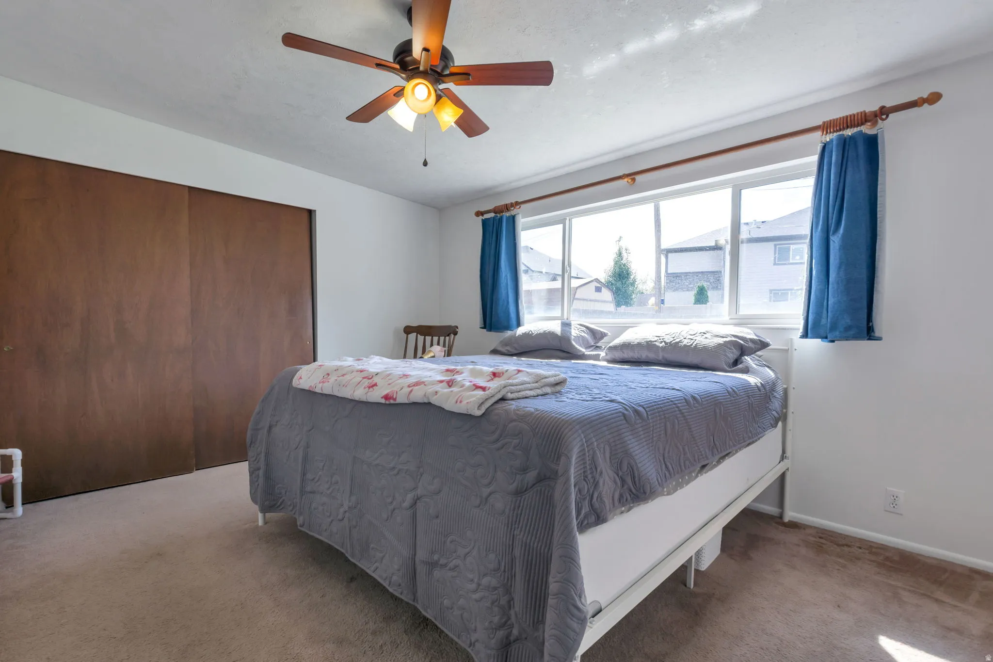 Recessed lighting, wood-finish ceiling fan, large pane windows, wood-paneled sliding closet doors, and neutral carpeting