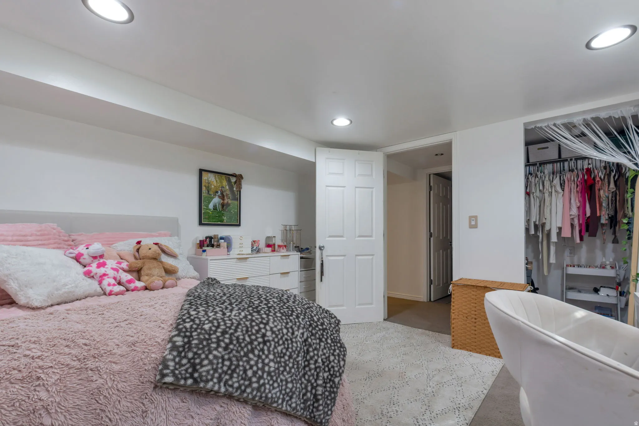 Spacious bedroom suite featuring neutral carpeting, recessed ceiling lighting, and an expansive walk-in closet with dual hanging rods and shelving