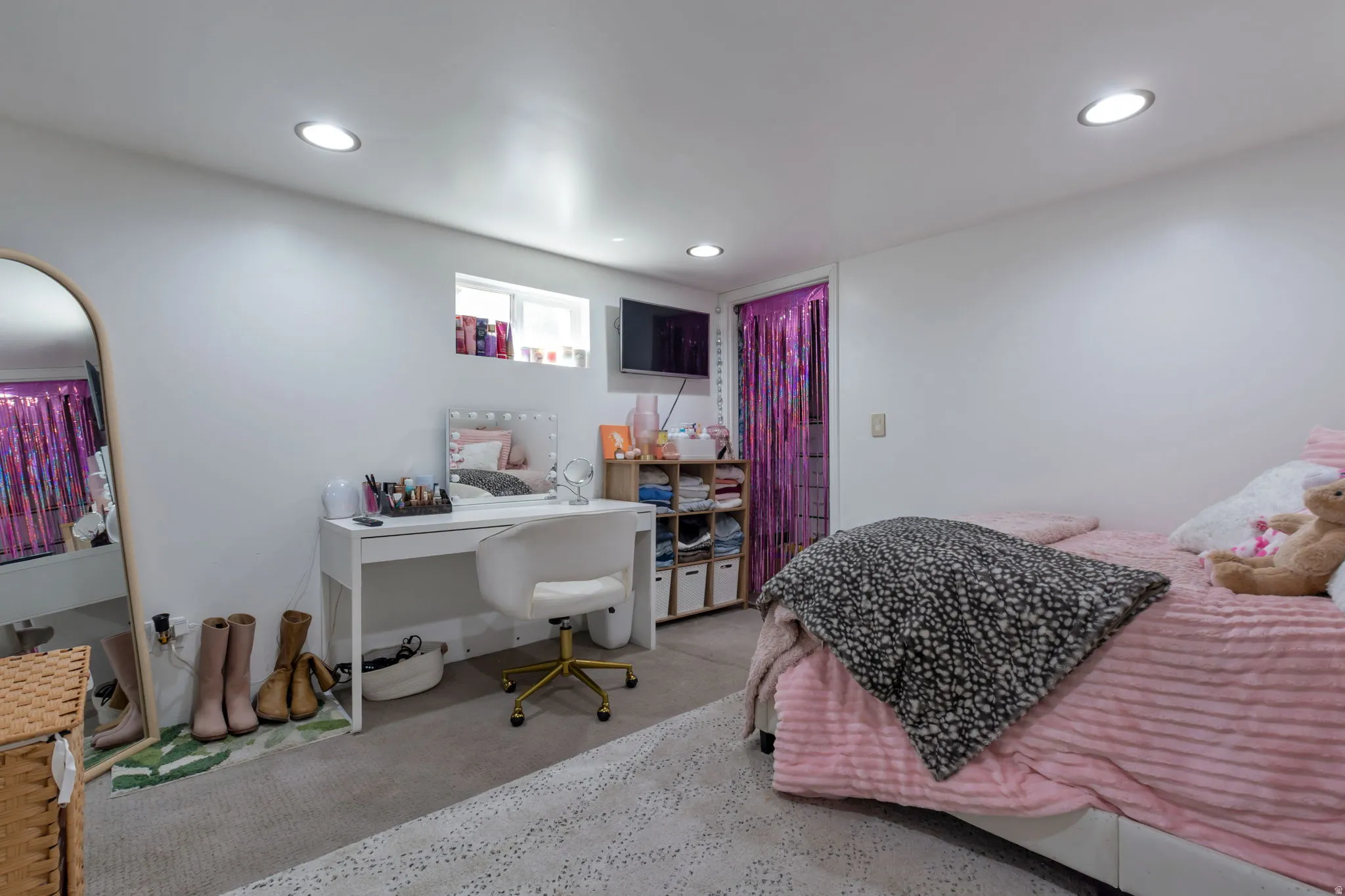 Recessed ceiling lighting, white walls, built-in shelving, mounted television, and a window for natural light