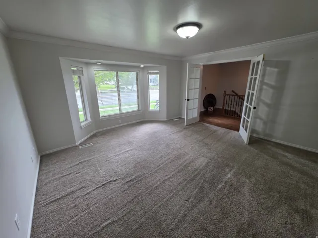 Recessed lighting and a bay window illuminate this carpeted room
