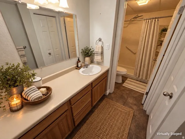 Bathroom featuring a single vanity with wood-finish cabinetry, a neutral countertop, a large wall mirror, and a shower with a grab bar