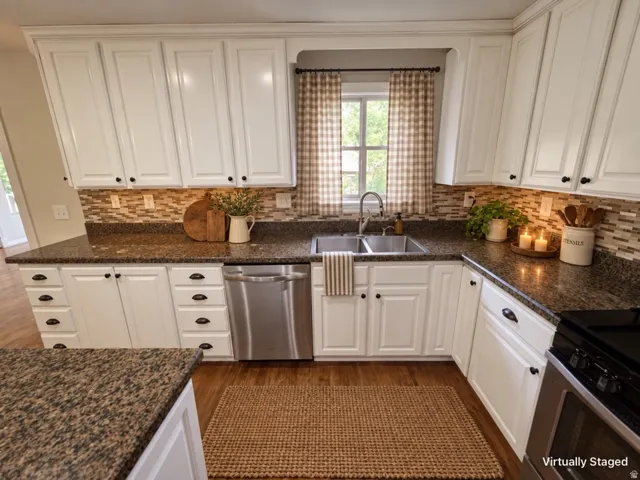 White cabinetry with dark hardware, granite-style countertops, stainless steel dishwasher, mosaic tile backsplash, and wood-finish flooring