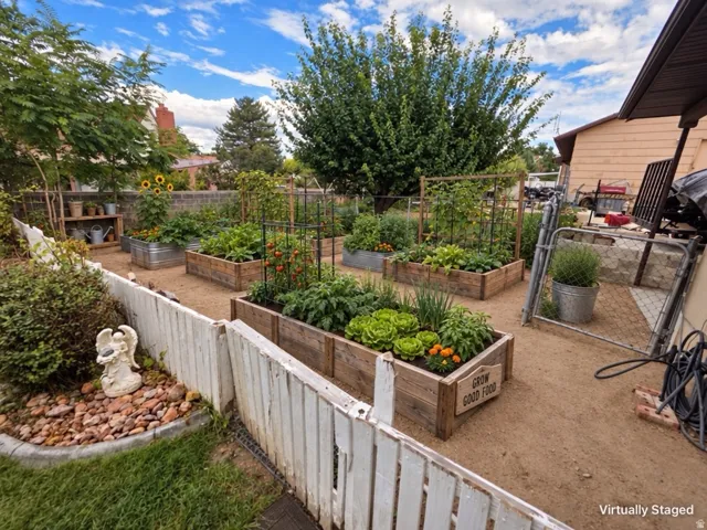 Expansive outdoor garden featuring multiple raised garden beds, a gravel pathway, and a white picket fence
