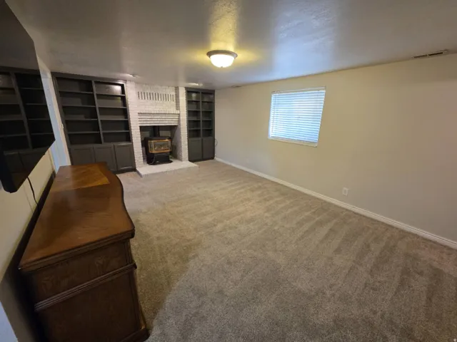 Built-in shelving flanking a white brick fireplace with a wood-burning stove