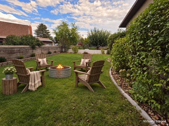 Expansive lawn area featuring a fire pit, concrete block retaining wall, and established perimeter landscaping