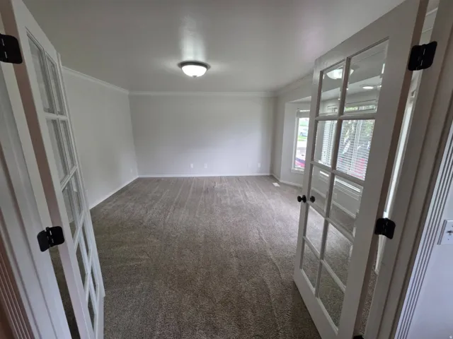 French doors with divided lites, crown molding, wall-to-wall carpeting, and bay windows with blinds