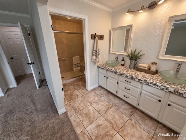 Dual vanity with glass vessel sinks, white cabinetry, and a mosaic tile countertop