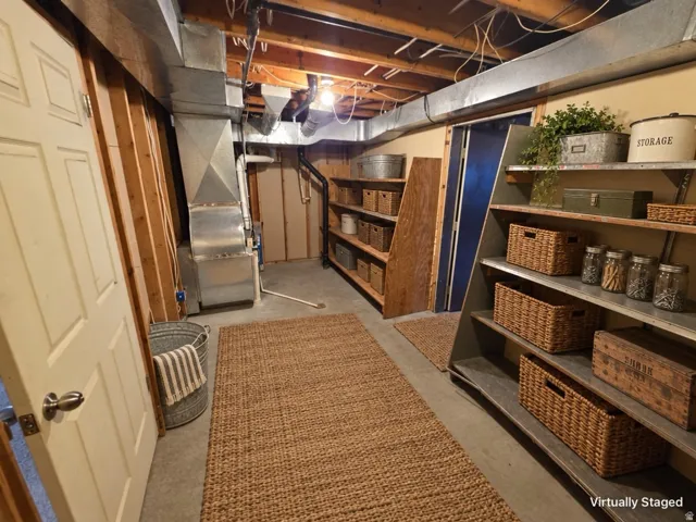 Exposed ceiling joists, concrete flooring, and extensive built-in shelving units provide ample storage