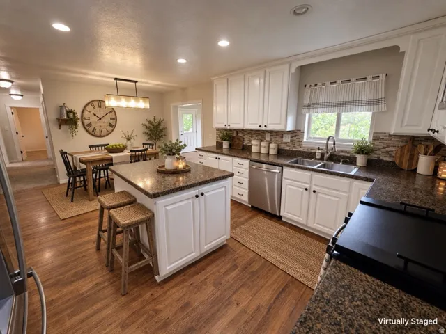 Kitchen featuring wood-finish flooring, white cabinetry, a central island with countertop, and stainless steel appliances
