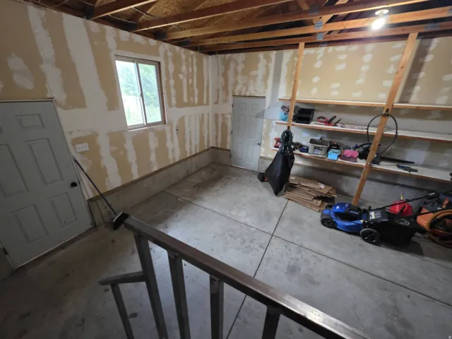 Concrete flooring, exposed ceiling joists, built-in shelving, interior access door, exterior-facing window