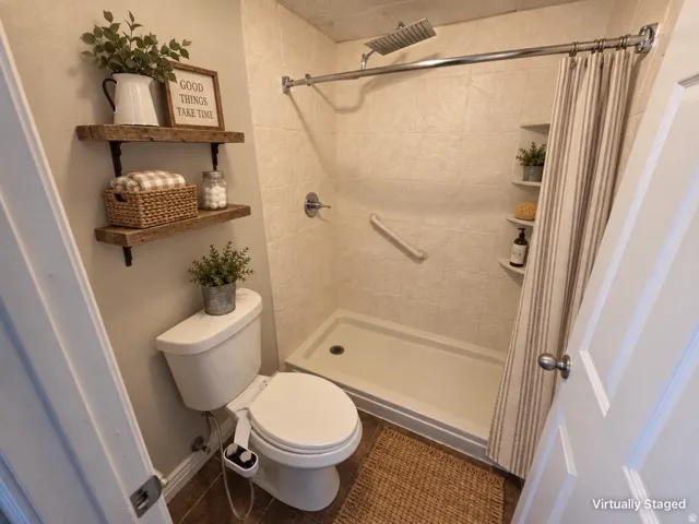 Walk-in shower with a rain showerhead, tiled walls, and built-in corner shelving