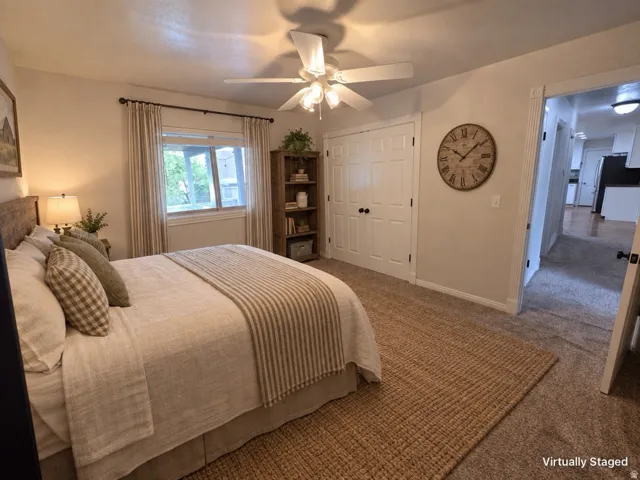Carpeted flooring, ceiling fan, white paneled doors, and window with curtains