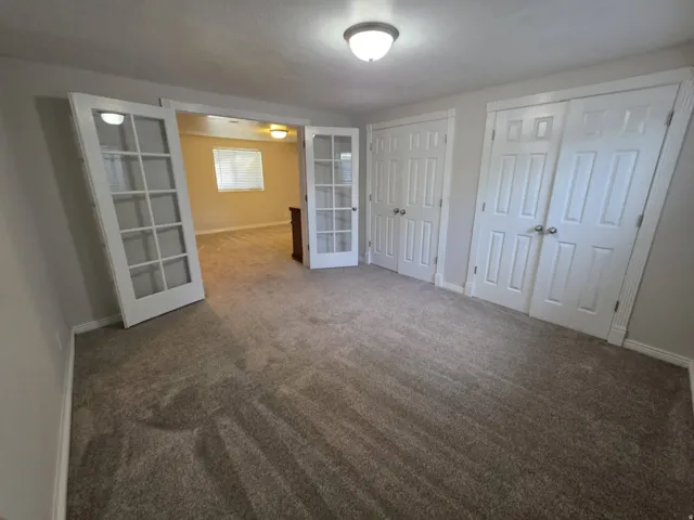 Plush carpet flooring, white paneled doors, and French doors with glass inserts