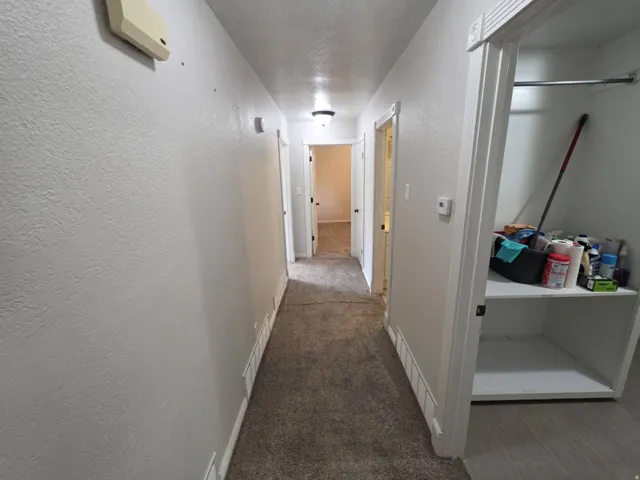 Hallway with carpeted flooring, textured walls, and recessed lighting