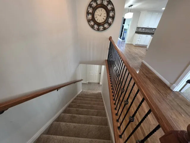 Hardwood-style flooring, white baseboards, and a staircase featuring wrought iron balusters and a wood handrail