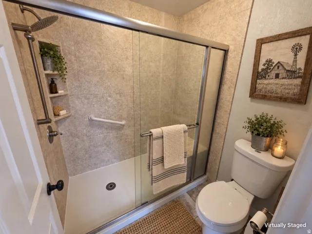 Tiled shower with a rain showerhead, built-in shelving, and grab bar