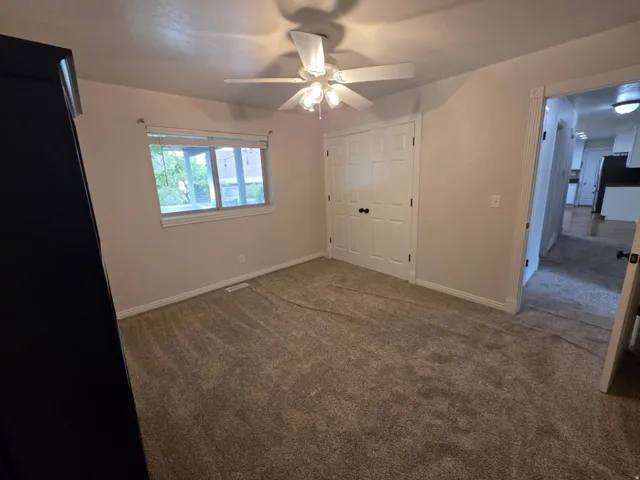 Room with neutral-toned carpet, a ceiling fan with integrated lighting, and a window with white trim