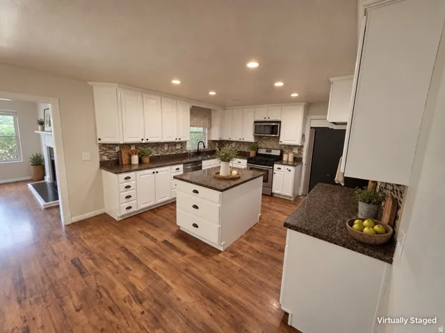 Kitchen featuring white cabinetry, wood-finish flooring, recessed lighting, a center island, and dark speckled countertops