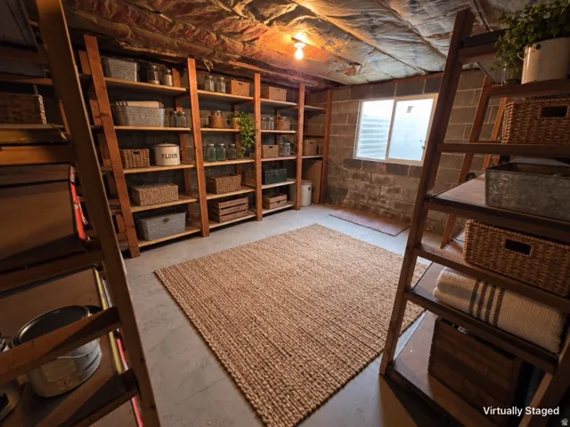Concrete flooring with a window, exposed ceiling insulation, and built-in wood shelving