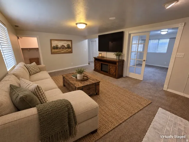 Living area with neutral carpeting, recessed closet, and French doors