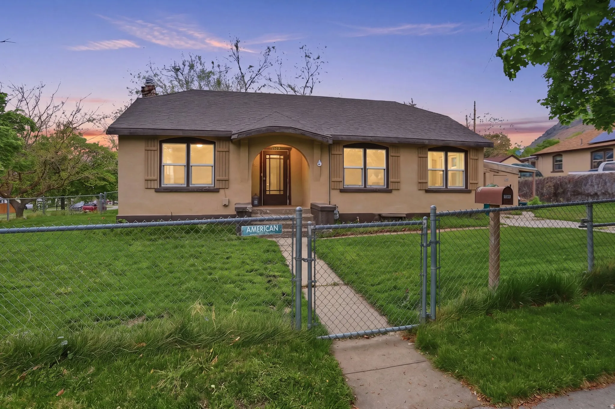 Stucco exterior, arched entry, panel door with glass insert, shuttered windows, and chain link fencing