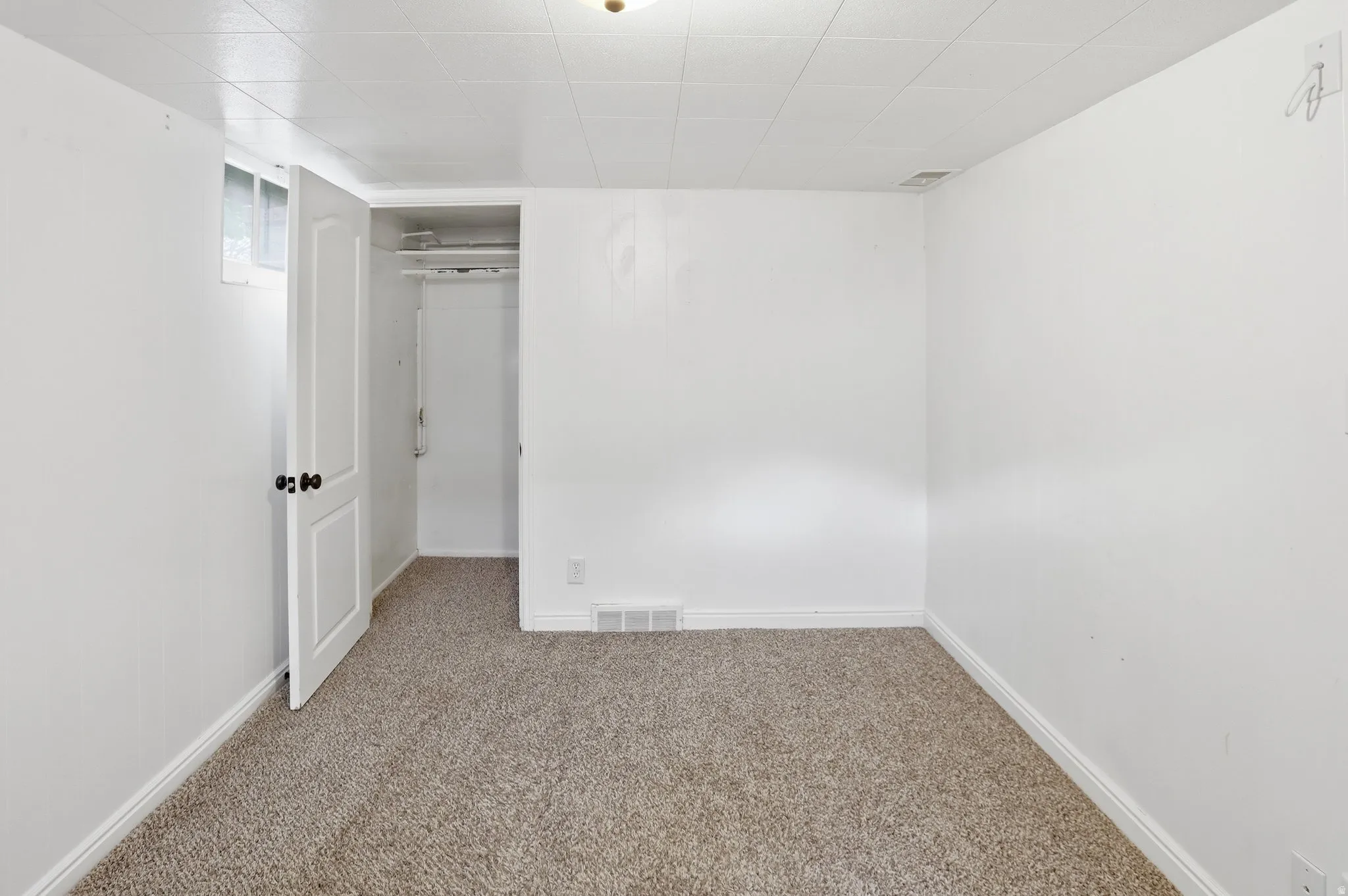 Carpeted flooring, white walls, white paneled door, and closet with shelving and hanging rod