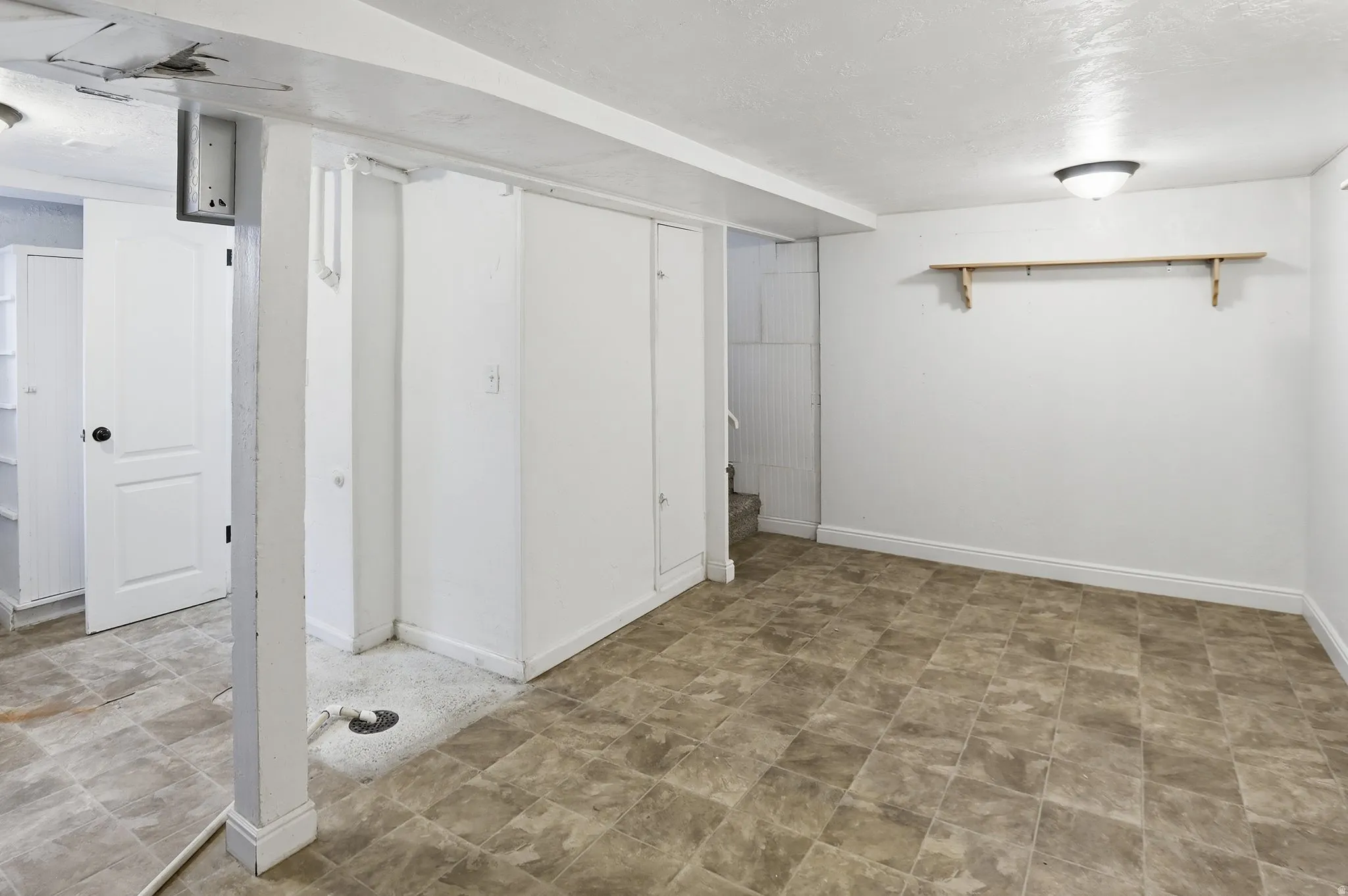 Spacious room featuring tiled flooring, white walls, built-in storage, and an overhead light fixture