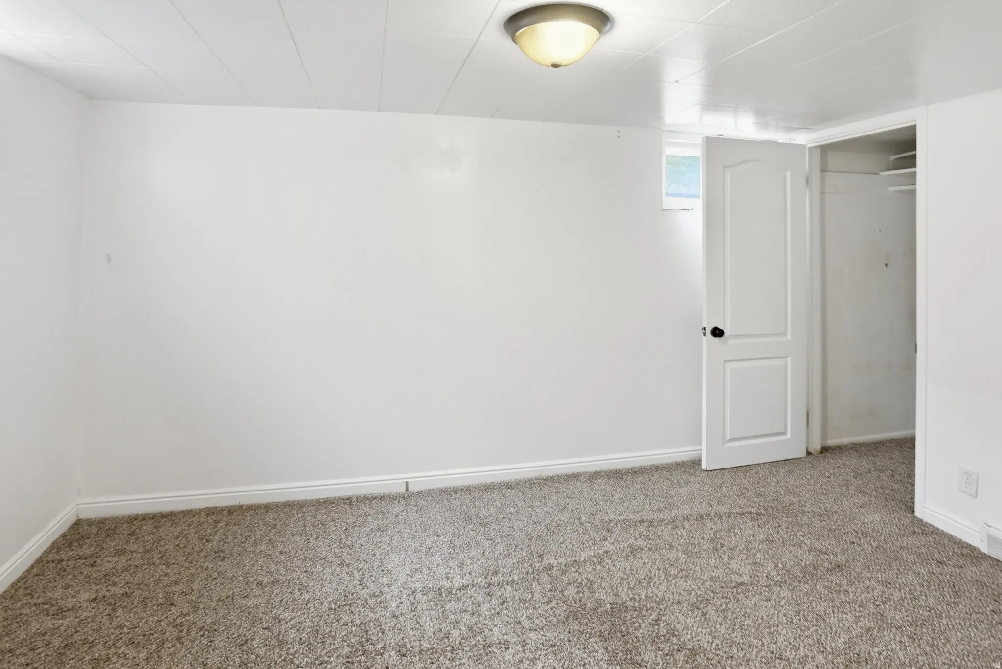 Wall-to-wall carpeting, recessed window, and white interior door with dark hardware