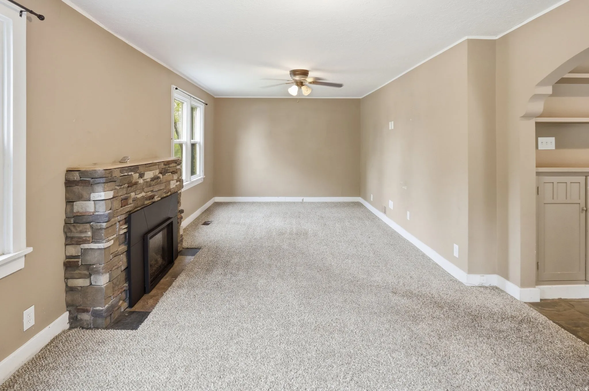 Spacious room with a stone-clad fireplace and a built-in cabinet with shelving