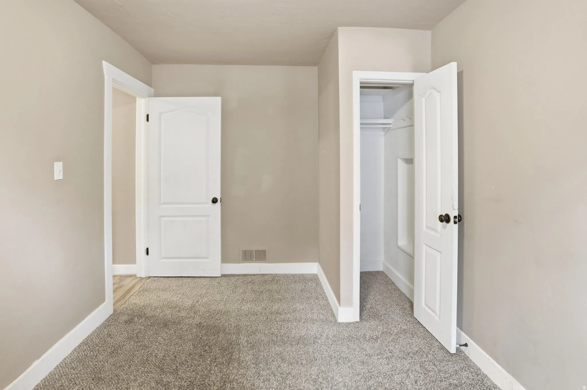 Soft gray carpeting, neutral wall paint, white trim, and white paneled doors