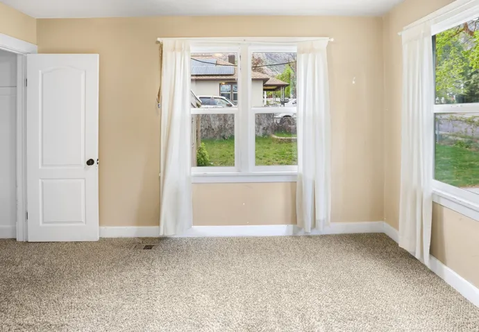 Textured carpet flooring, multiple windows, white trim, and a paneled door