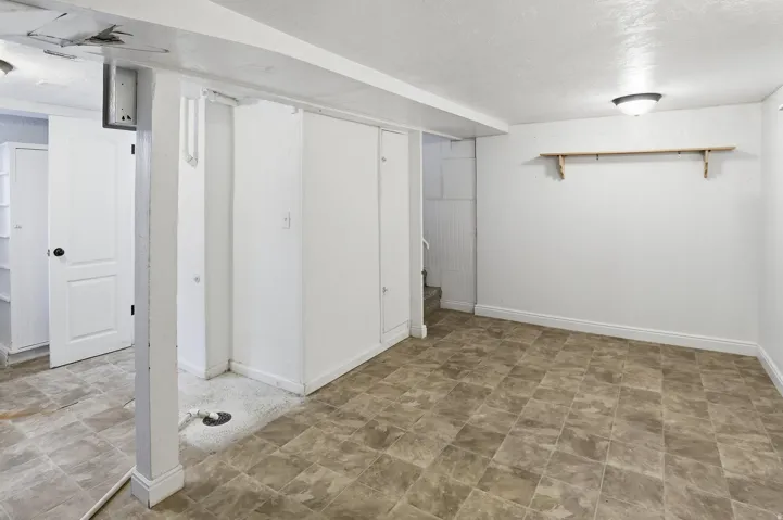 Spacious room featuring tiled flooring, white walls, built-in storage, and an overhead light fixture