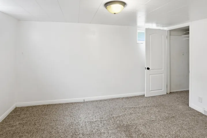 Wall-to-wall carpeting, recessed window, and white interior door with dark hardware