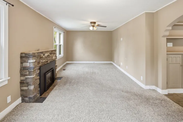 Spacious room with a stone-clad fireplace and a built-in cabinet with shelving