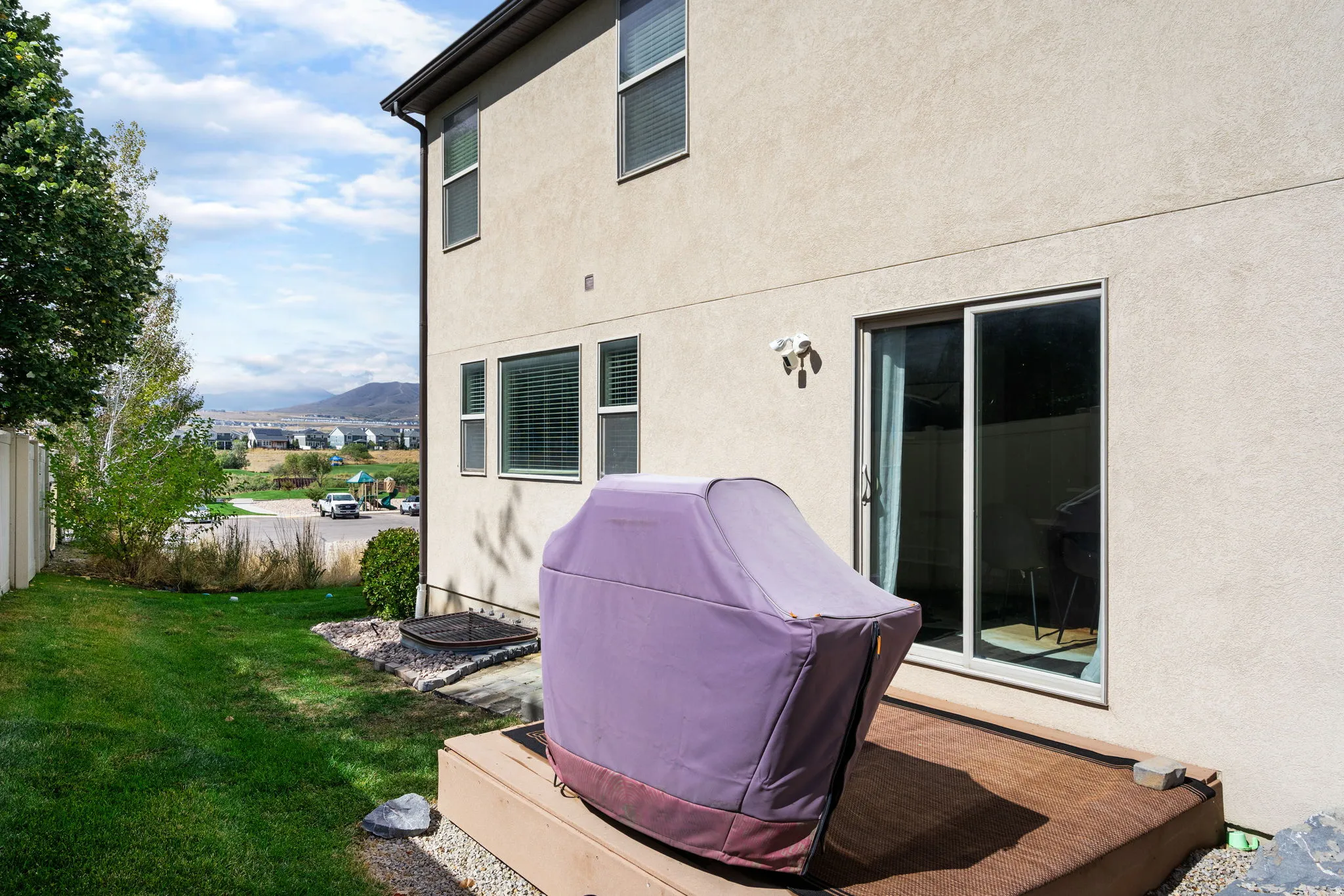 Stucco exterior with multiple windows, sliding glass door, and an exterior light fixture