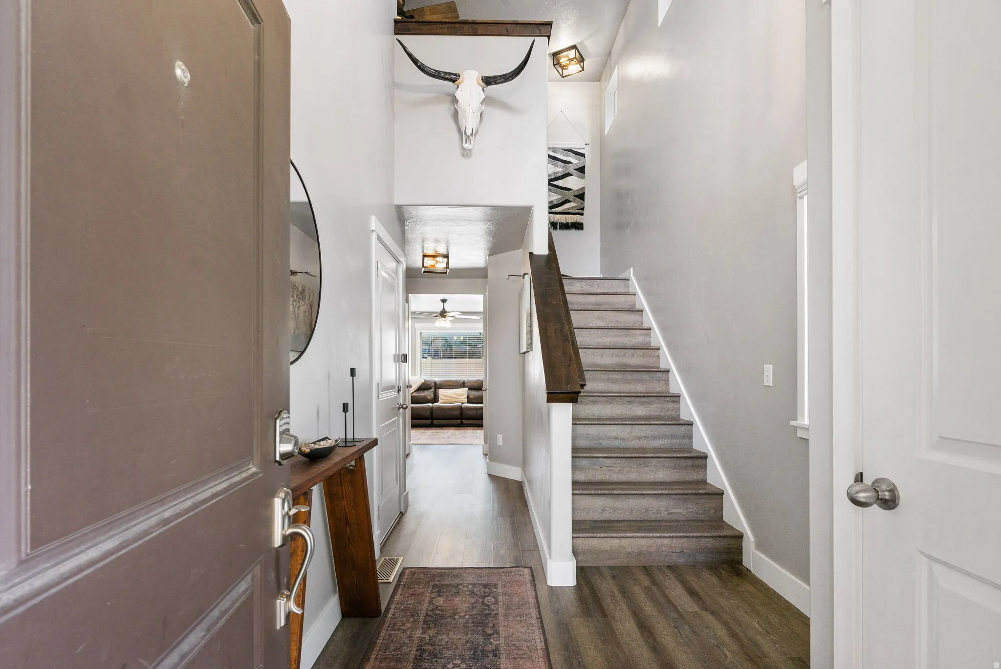 Inviting entryway featuring wood-finish flooring, a contemporary staircase with a dark wood handrail, and high ceilings