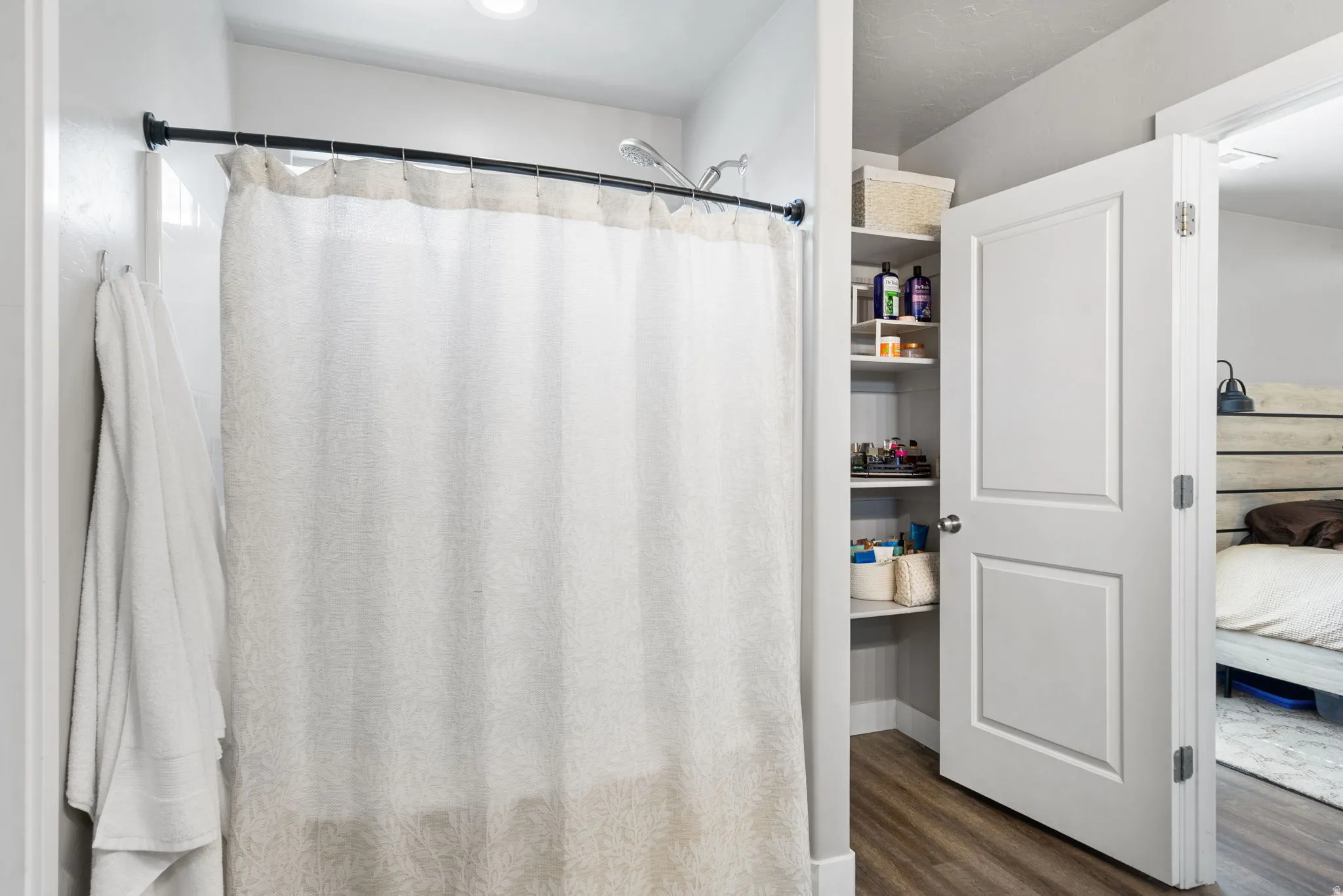 Built-in shelving for storage, white paneled door, wood-finish flooring