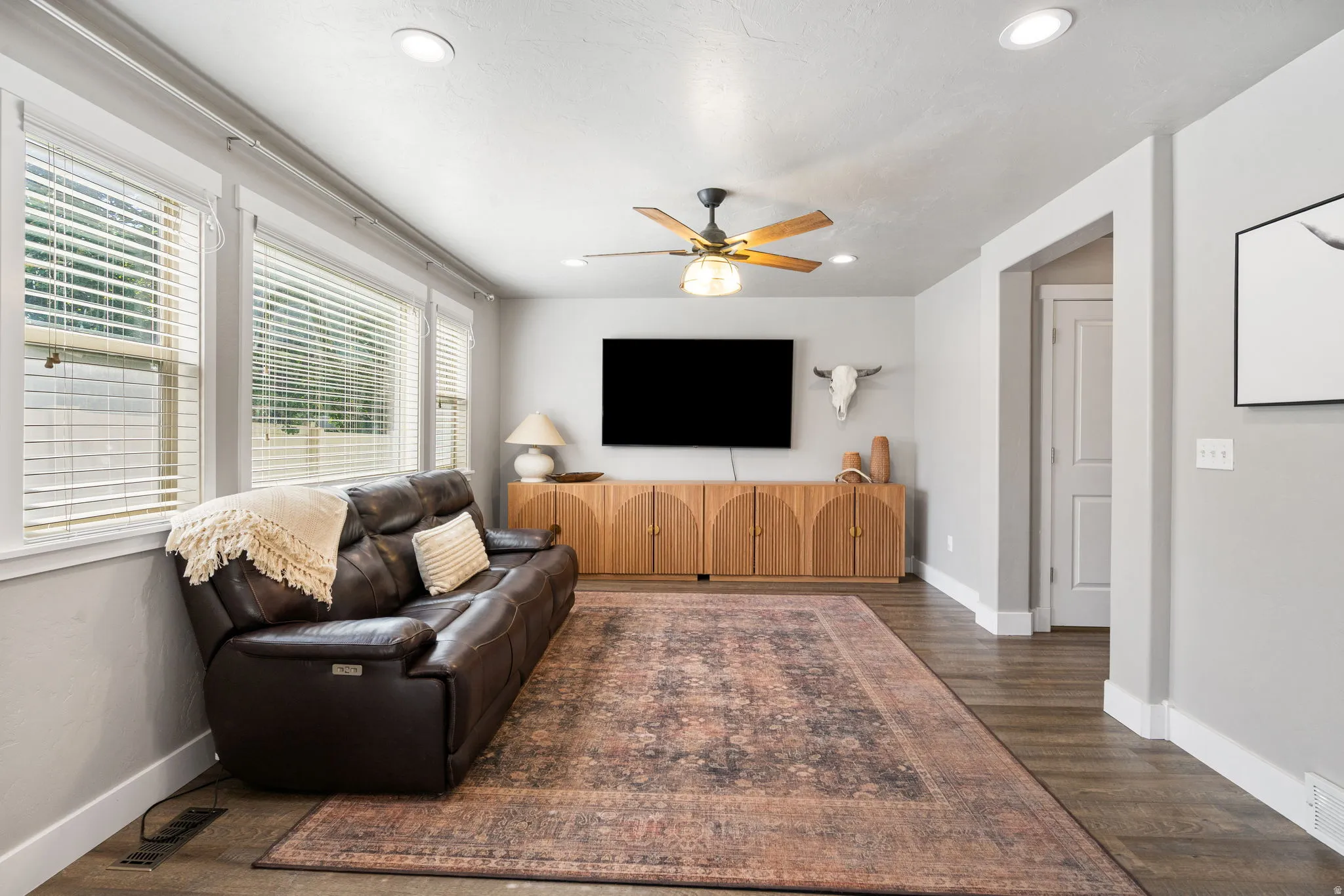 Recessed ceiling lights illuminate the spacious room with wood-finish flooring
