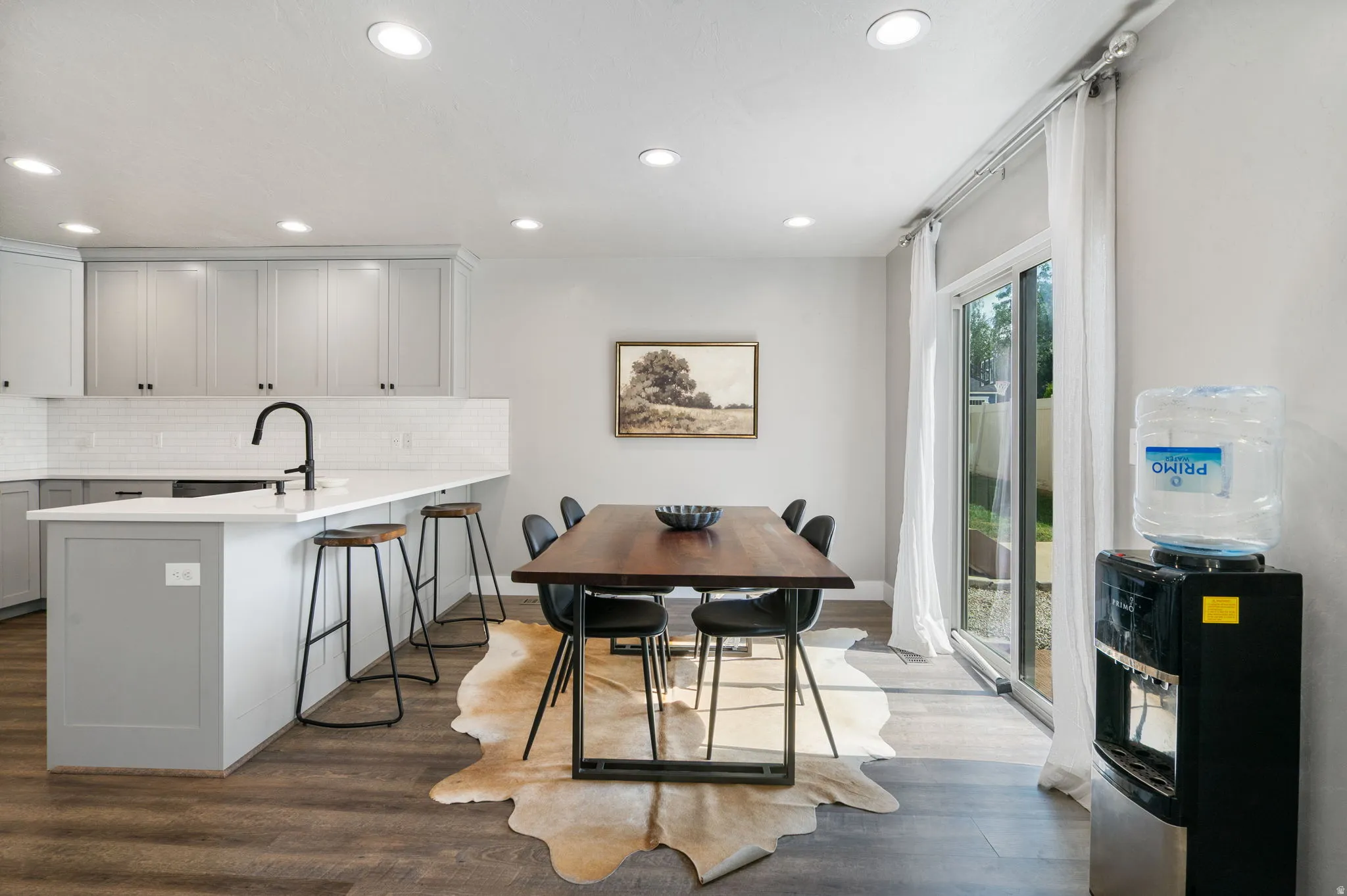 Modern kitchen with light gray cabinetry, white subway tile backsplash, and a large island with seating