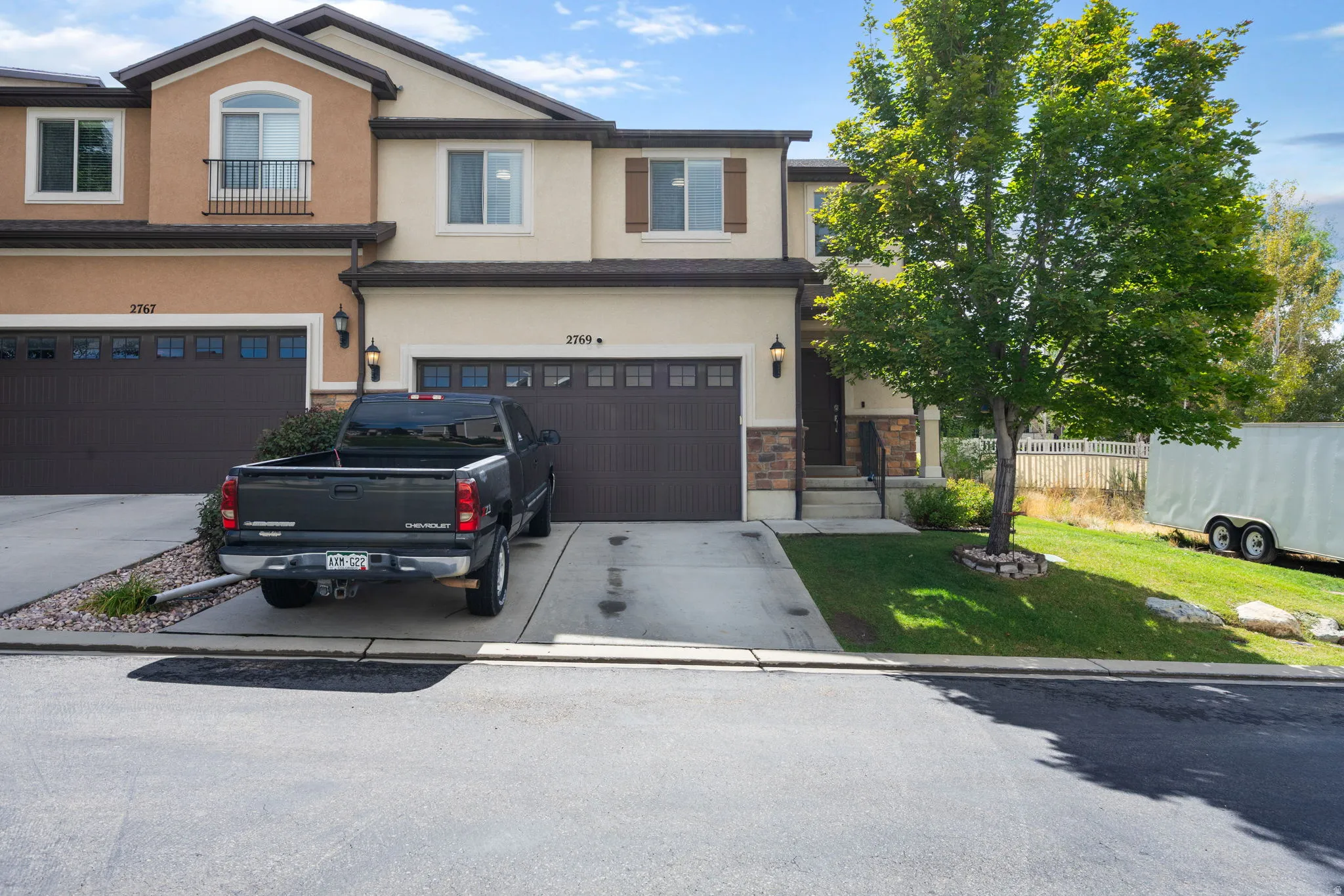 Two-story exterior with a two-tone stucco facade, dark brown garage doors, and a covered entry