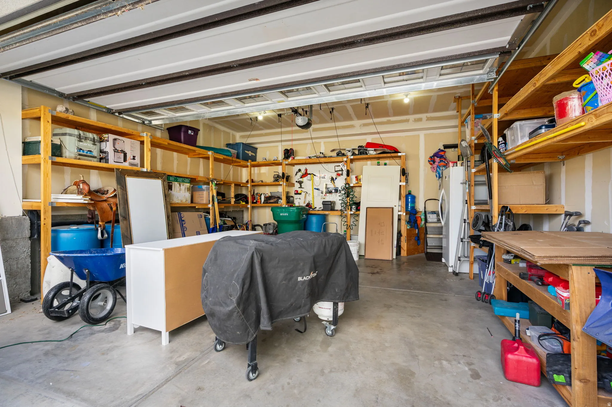 Expansive garage with concrete flooring, overhead garage door, and extensive built-in wooden shelving for storage